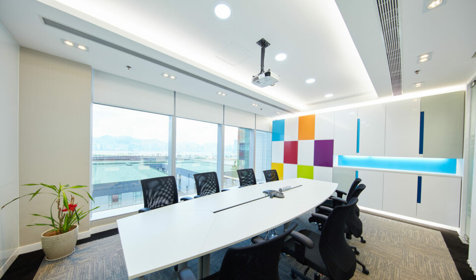 A boardroom without people, with white walls and large windows looking out to mountains in the distance