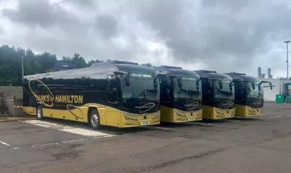 Four Plaxton Leoparad coaches stand in a row, all painted black and gold with Park's of Hamilton lettering.
