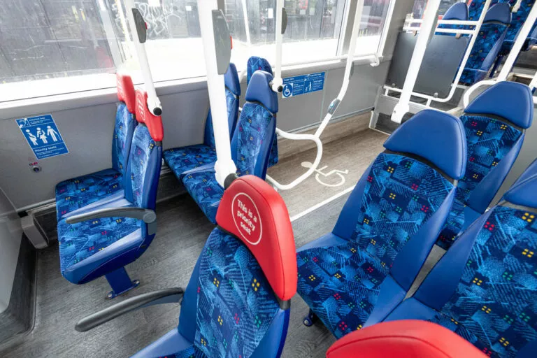 Interior of the middle section of a single deck bus, which priority seats and wheelchair bay visible